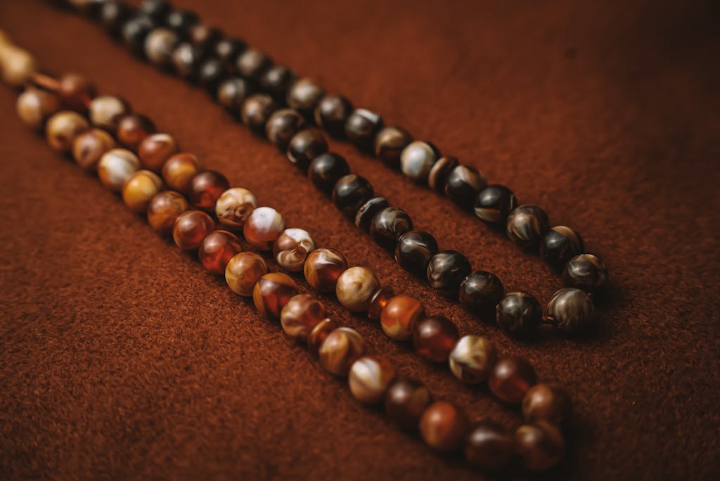 Close-up of beautifully crafted beaded necklaces on a soft, warm-toned fabric surface.